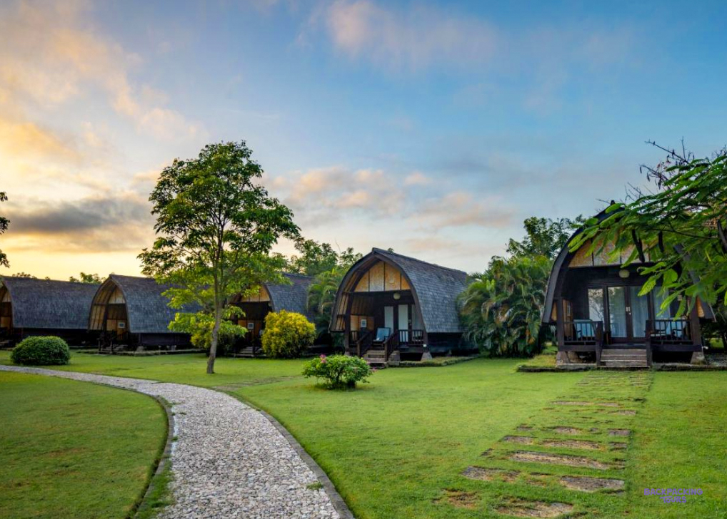 A path across the lawn to thatched bungalows at the seaside hotel in Sumbawa, at sunset
