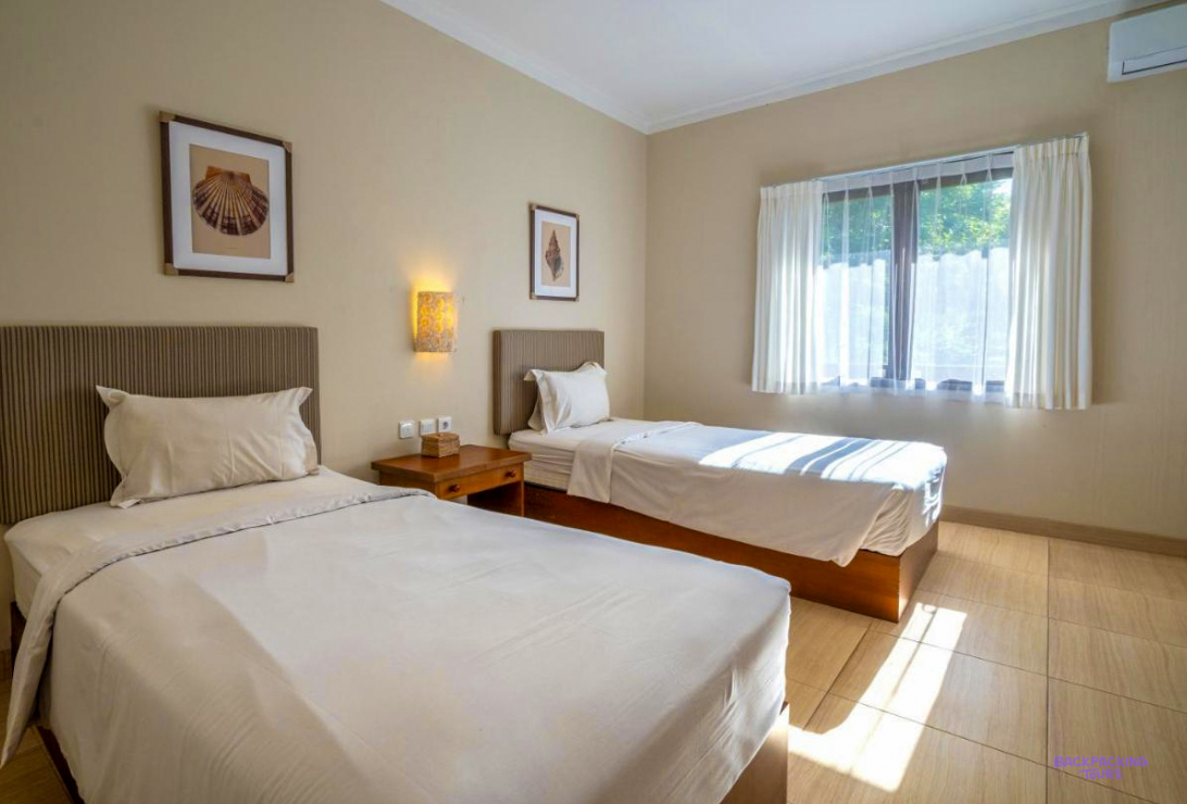 A twin room with white beds at the seaside hotel in Sumbawa