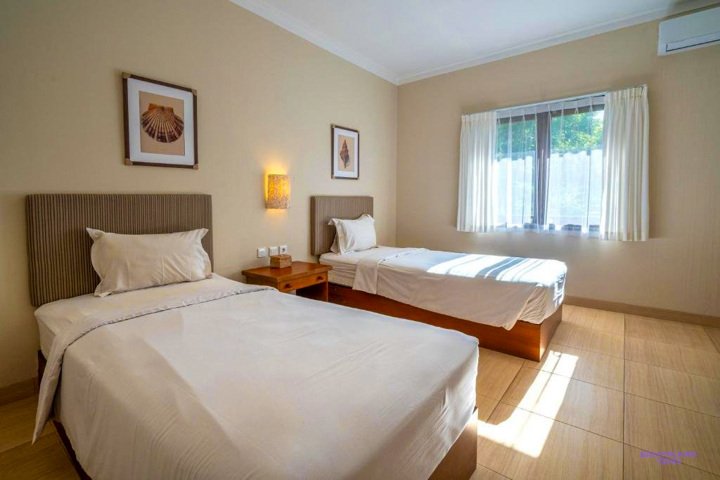 A twin room with white beds at the hotel in Sumbawa