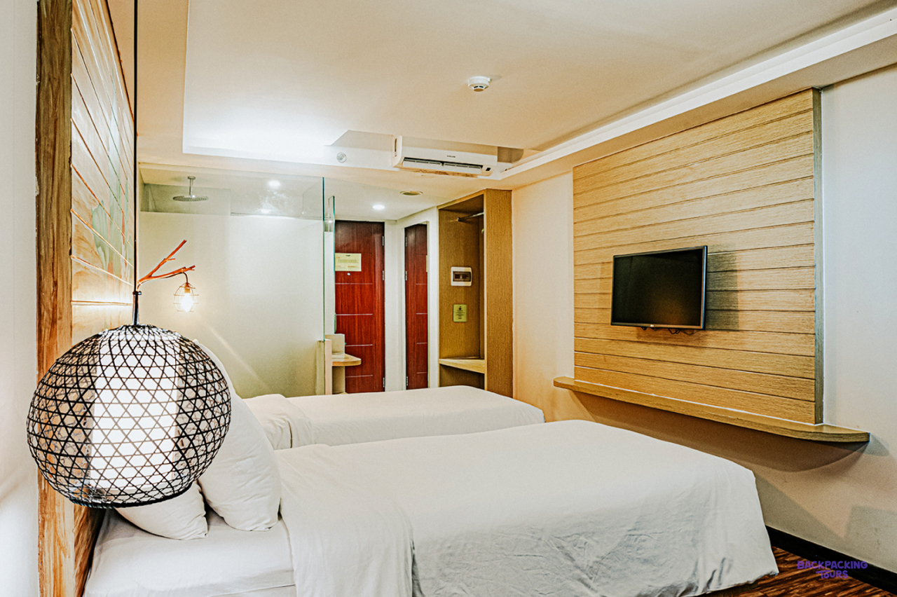 A twin room with a round woven lamp and wooden panelling at the hotel in Ubud