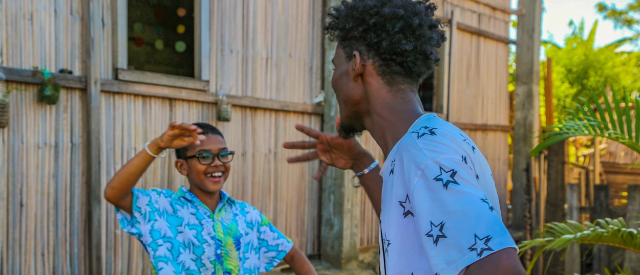 A young boy and an adult playing a hand game and laughing in Madagascar.