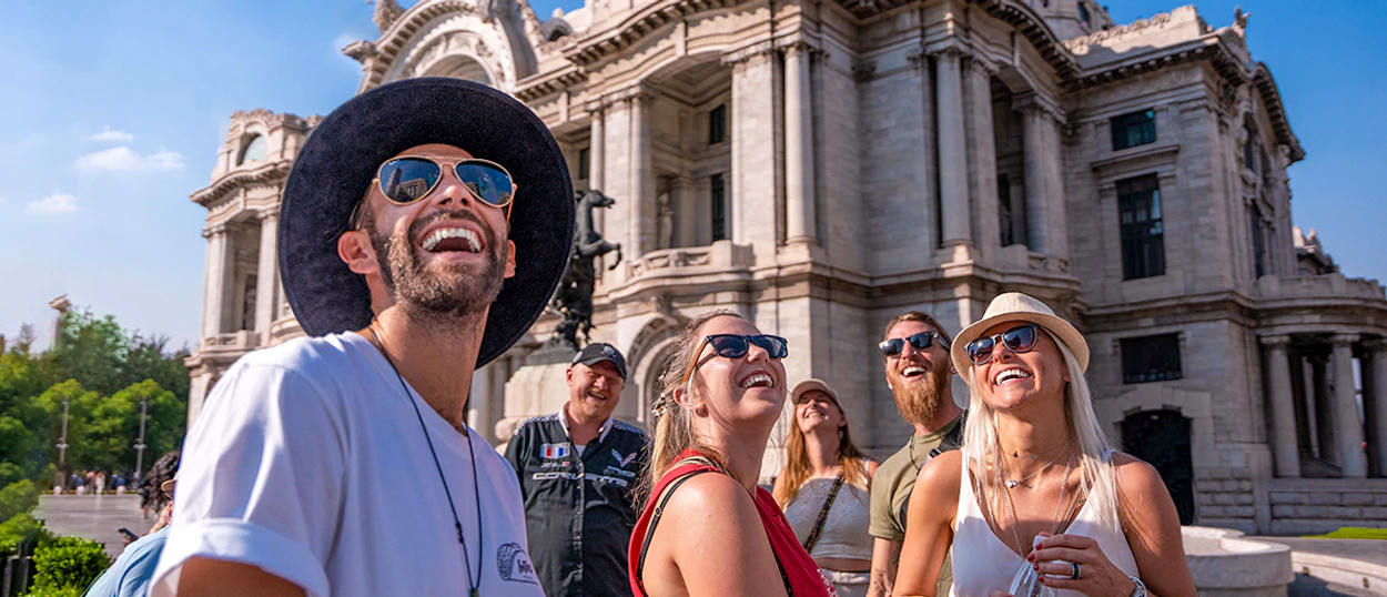 Happy backpackers admire the stunning architecture of the Palacio de Bellas Artes in Mexico City.