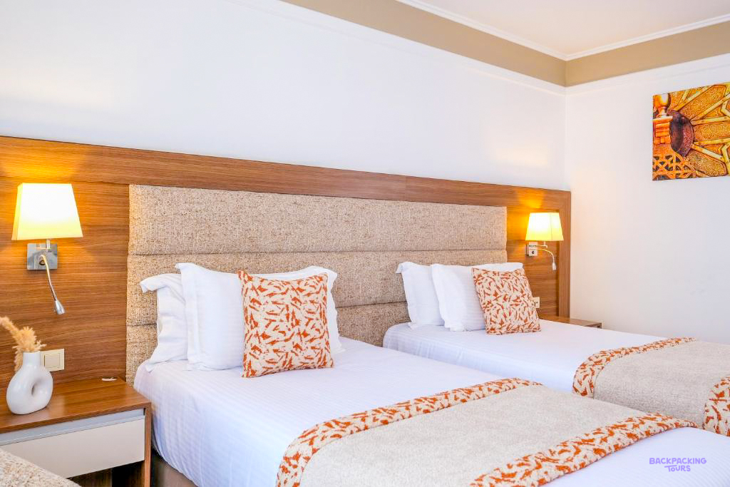 A twin room at Kenzi Basma Hotel in Casablanca, with white beds and orange patterned cushions.