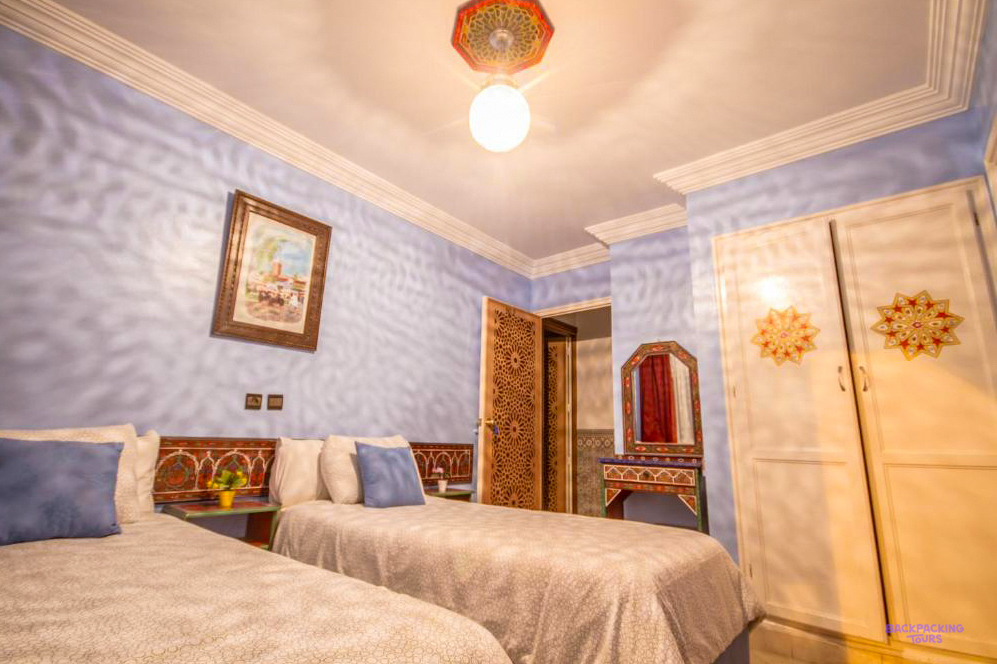 A twin room at Hotel Tarek in Chefchaouen with pale blue walls and a carved wooden door.