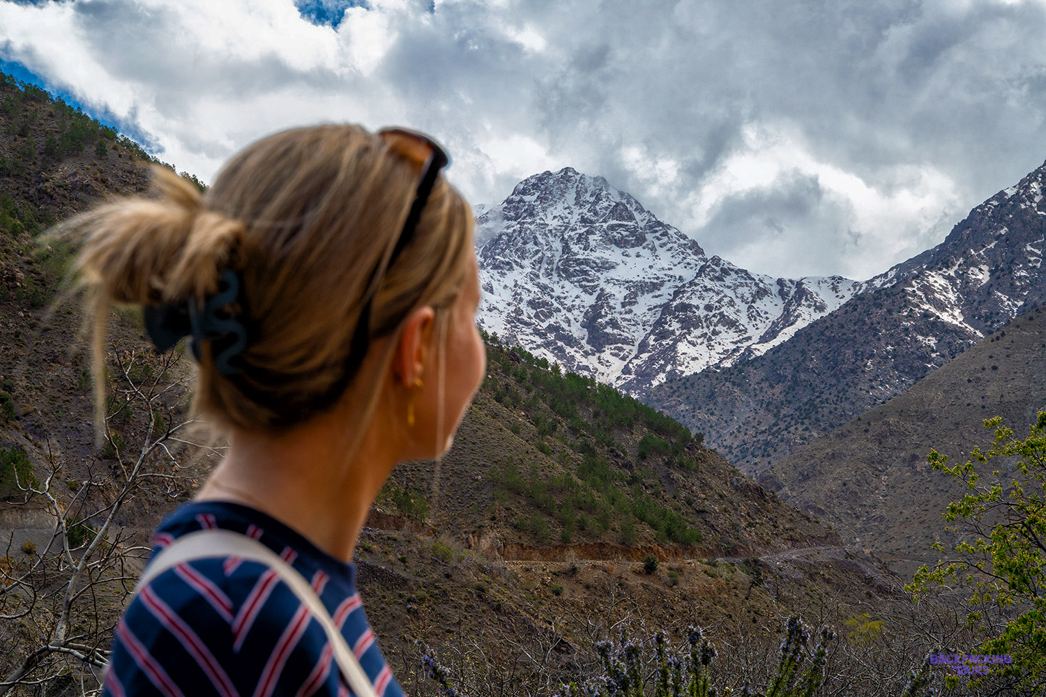 A traveller looks up at a snow-capped peak rising above the valleys around Imlil.
