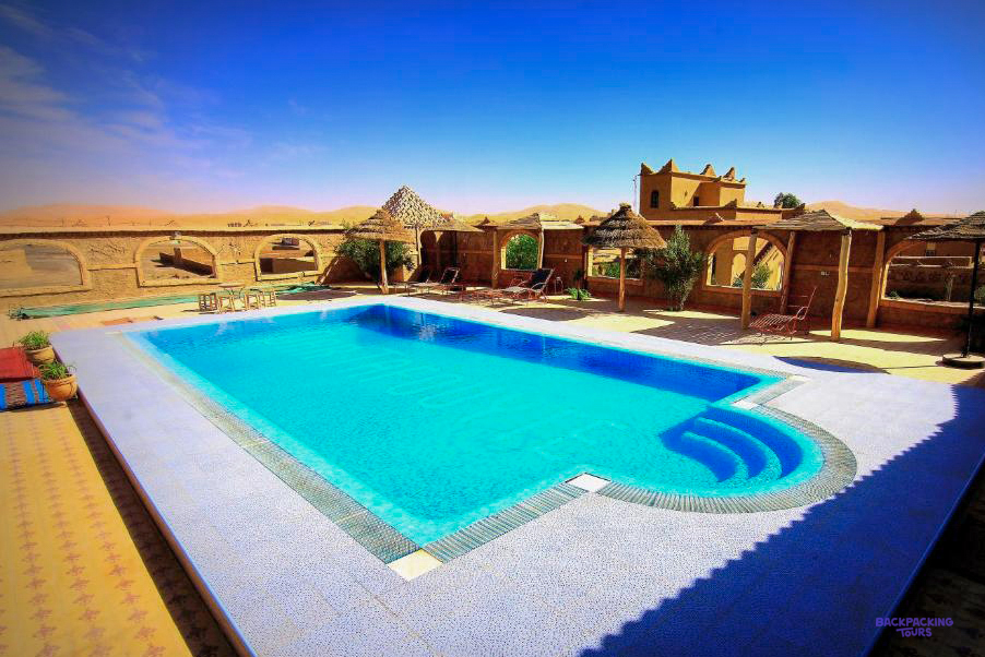 The swimming pool at Dar Tafouyte Riad, surrounded by earthen buildings on the edge of the desert.