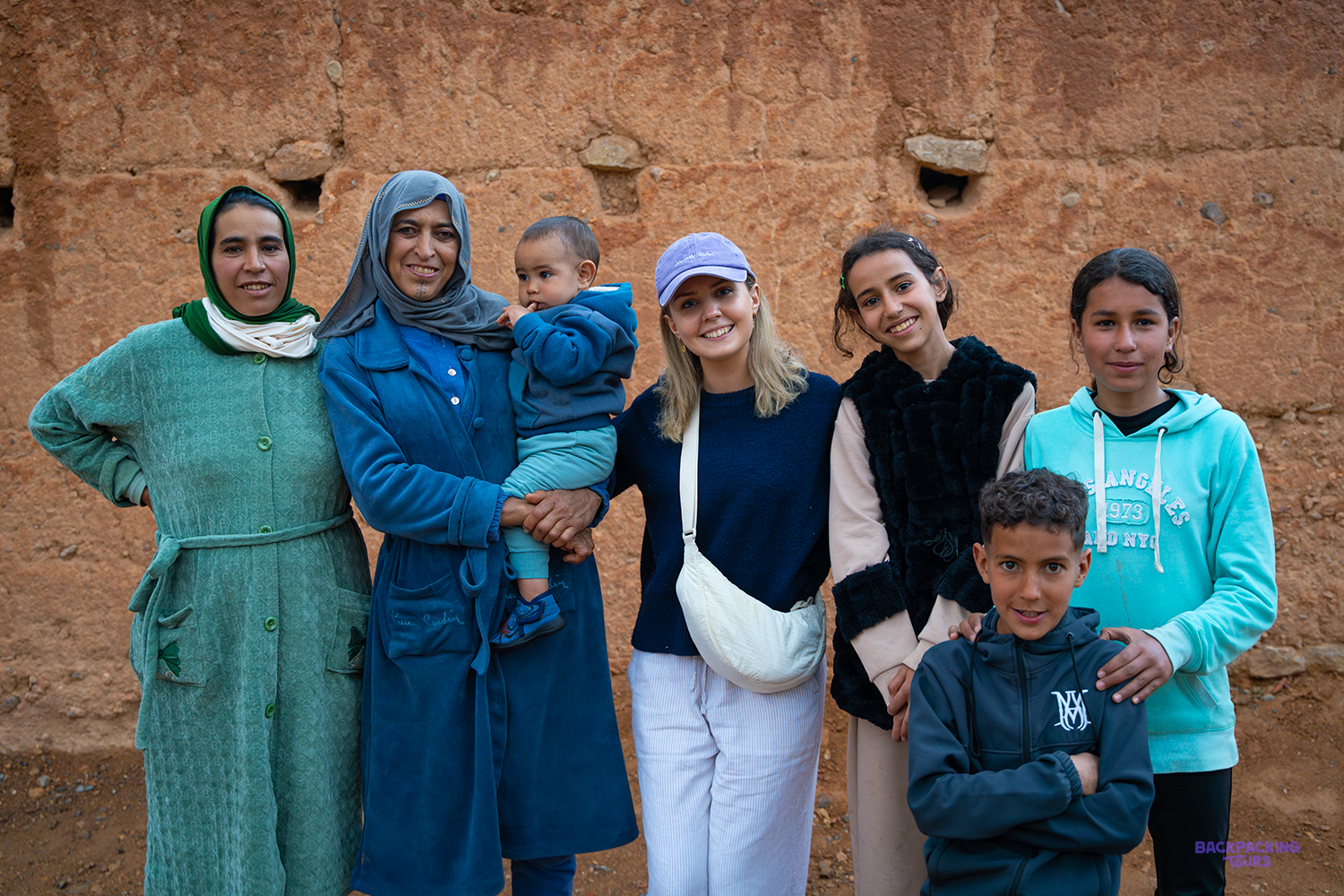 Travellers pose with a Berber family in front of a mud-brick wall in a village near Midelt.