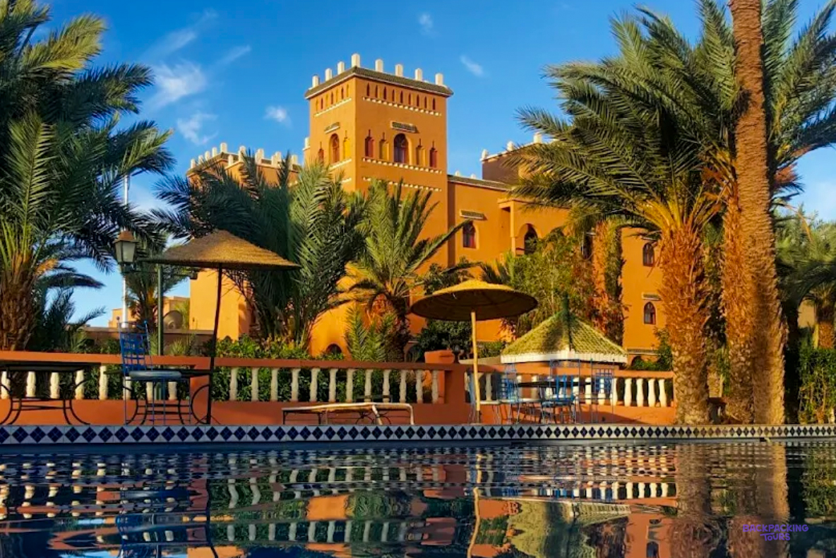 Hotel les Jardins de Ouarzazate, a kasbah-style building among palm trees beside its pool.