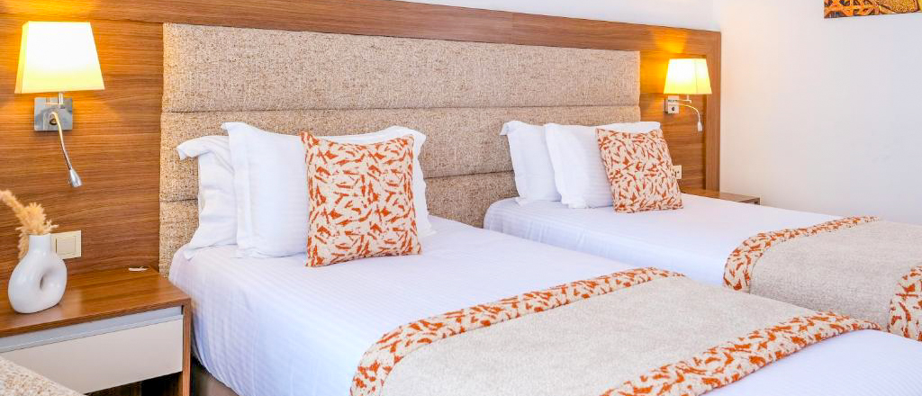 A twin room at Kenzi Basma Hotel in Casablanca, with white beds and orange patterned cushions.