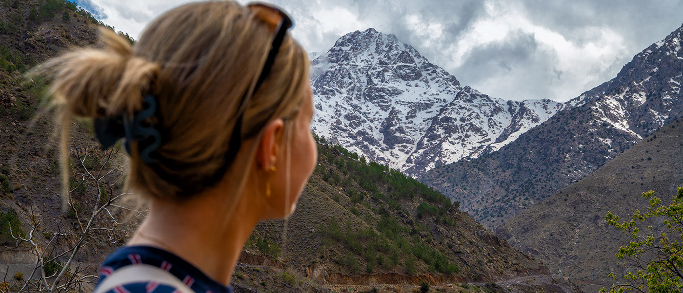 A traveller looks up at a snow-capped peak rising above the valleys around Imlil.