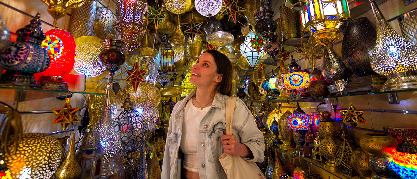 A traveller looks up at hundreds of glowing metal lanterns in a shop in the Marrakech medina.