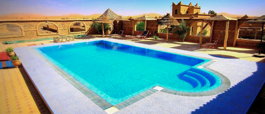 The swimming pool at Dar Tafouyte Riad, surrounded by earthen buildings on the edge of the desert.