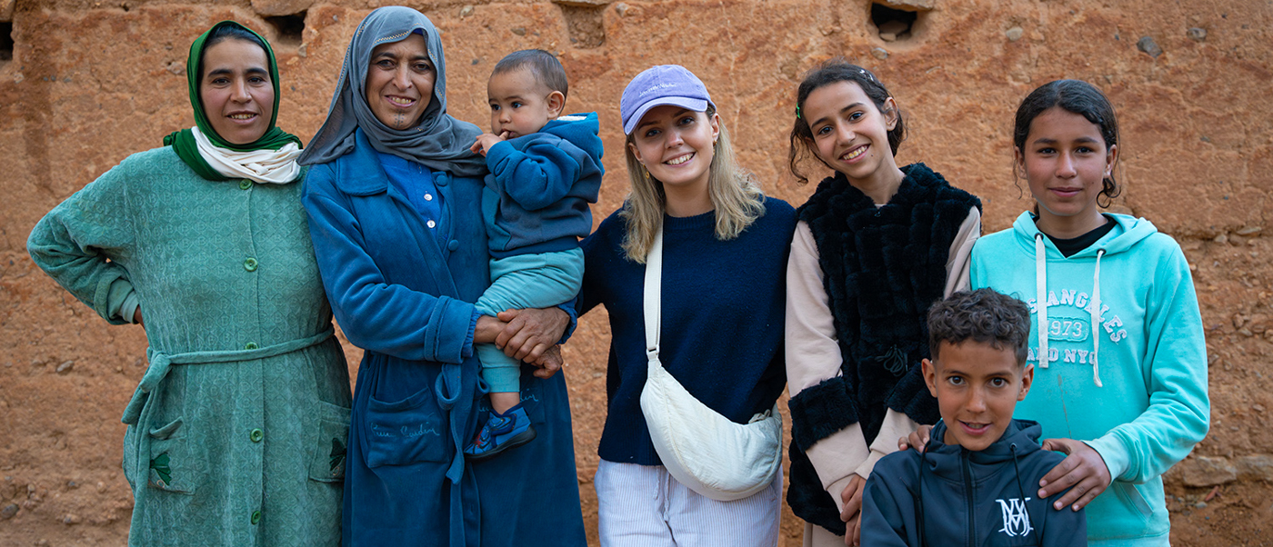 Travellers pose with a Berber family in front of a mud-brick wall in a village near Midelt.