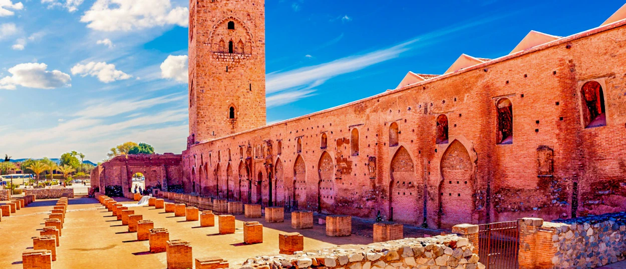 The majestic Koutoubia Mosque minaret and ancient ruins under a clear blue sky in Marrakech.