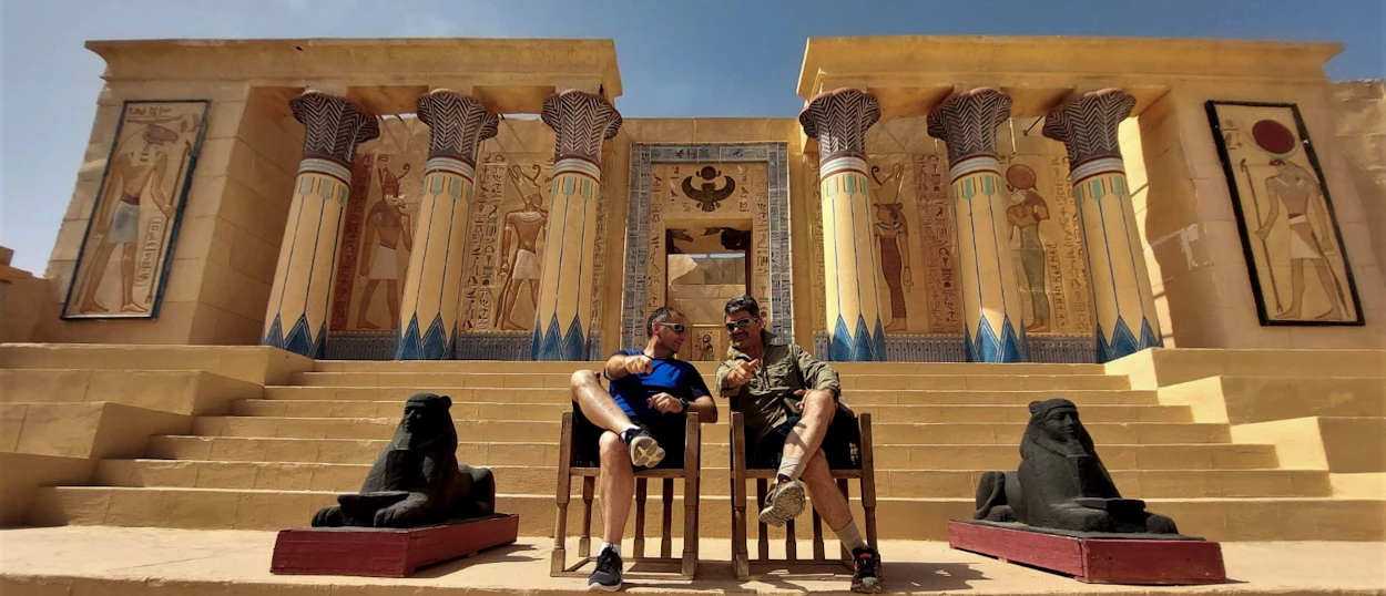 Two men pose in front of an elaborate ancient Egyptian movie set at Atlas Studios, Morocco.