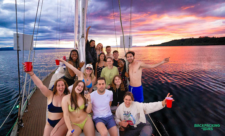 A group of happy backpackers enjoying a beautiful sunset cruise on Lake Taupo, New Zealand.