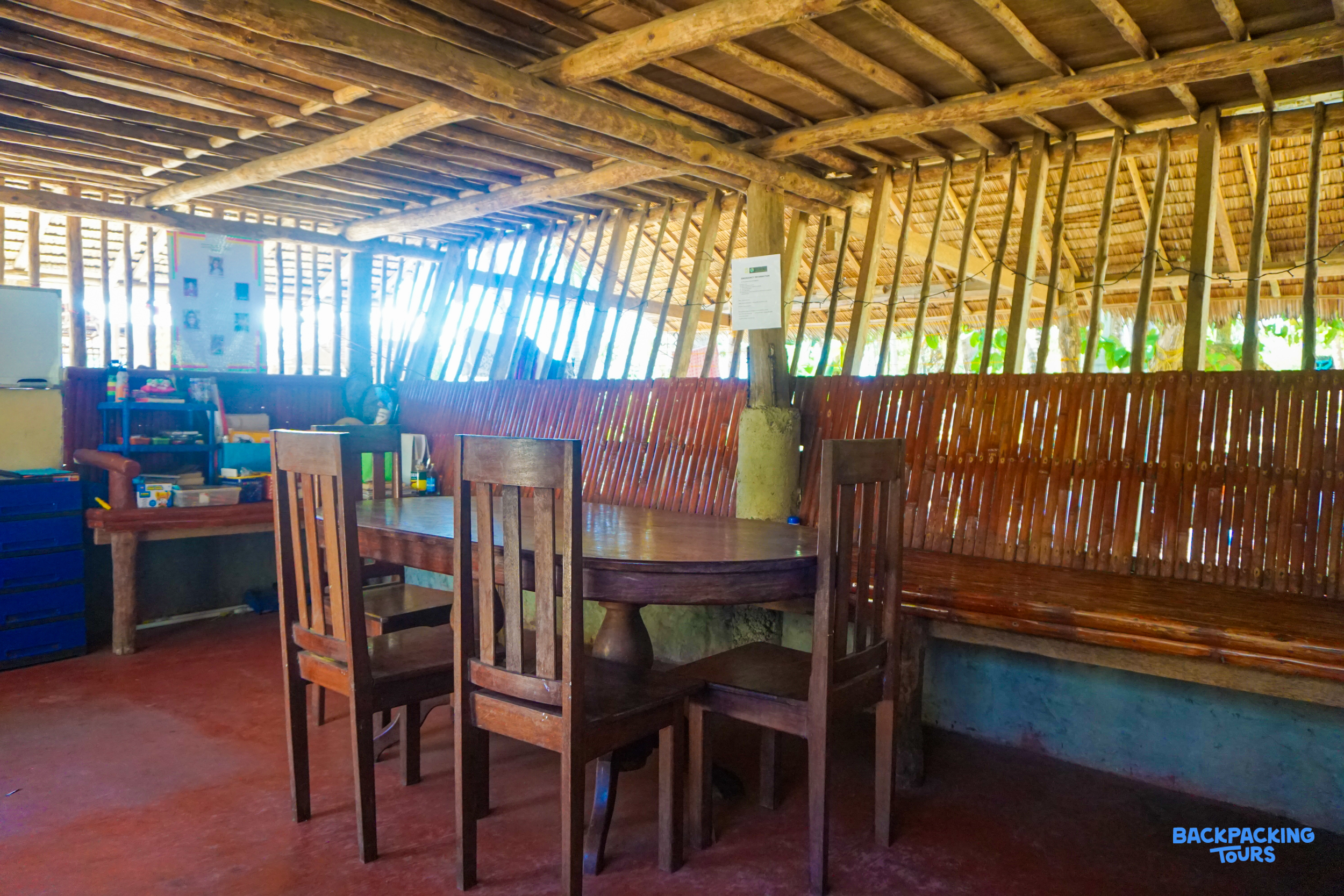 Rustic common area with wooden table, chairs, and bamboo walls in the Philippines.