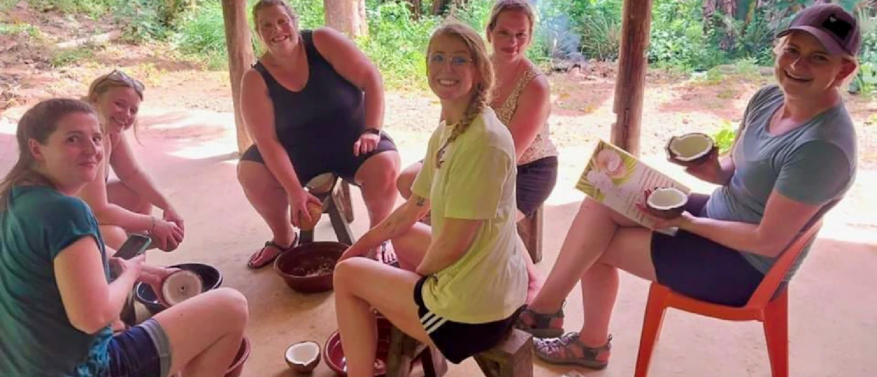 Six happy women learning to prepare coconuts for cooking during a cultural activity in El Nido.