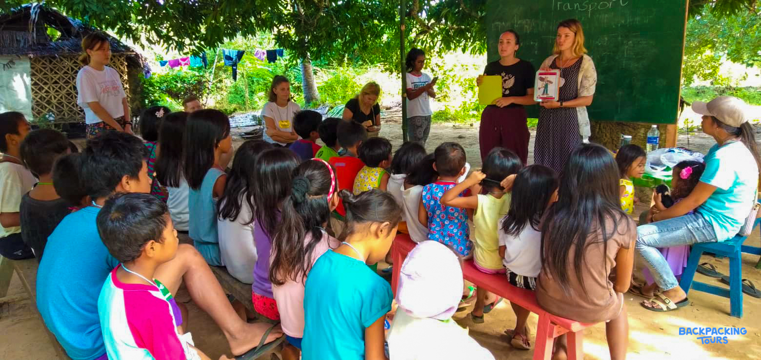 A group of children learn about global warming from volunteers in an outdoor classroom in the Philippines.