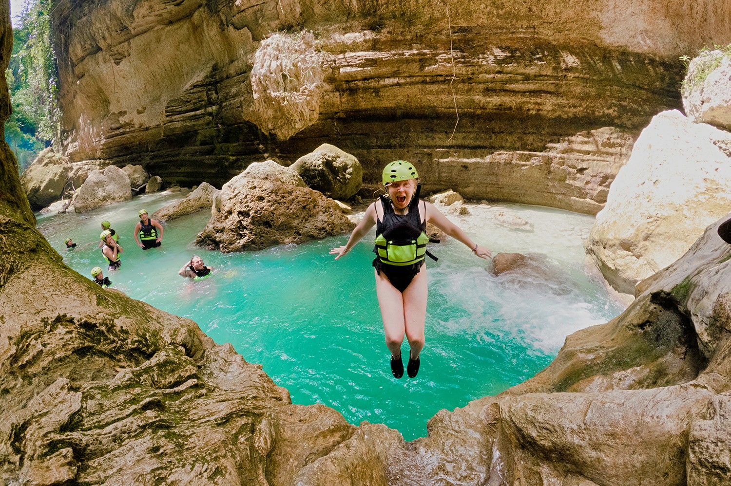 A backpacker leaping into the bright blue pools of Kawasan Falls in Cebu.