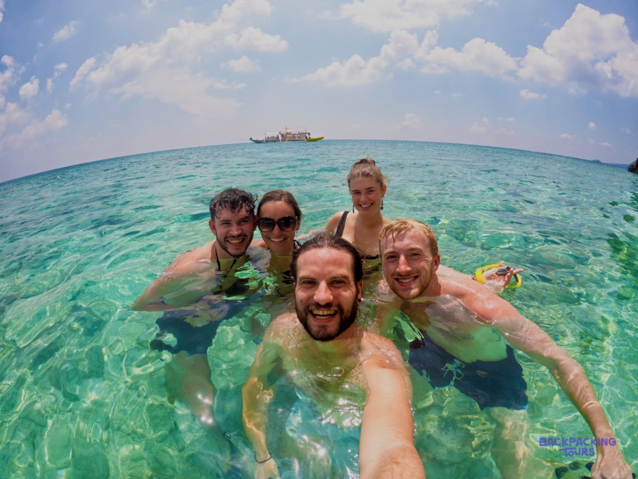 Friends taking a selfie on a deserted beach during the Palawan boat expedition.