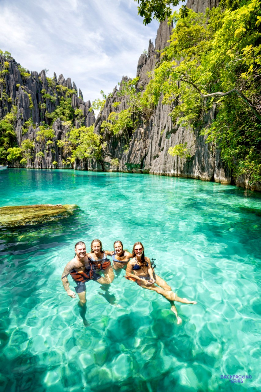 A group of travellers swimming together in a hidden lagoon in Palawan.