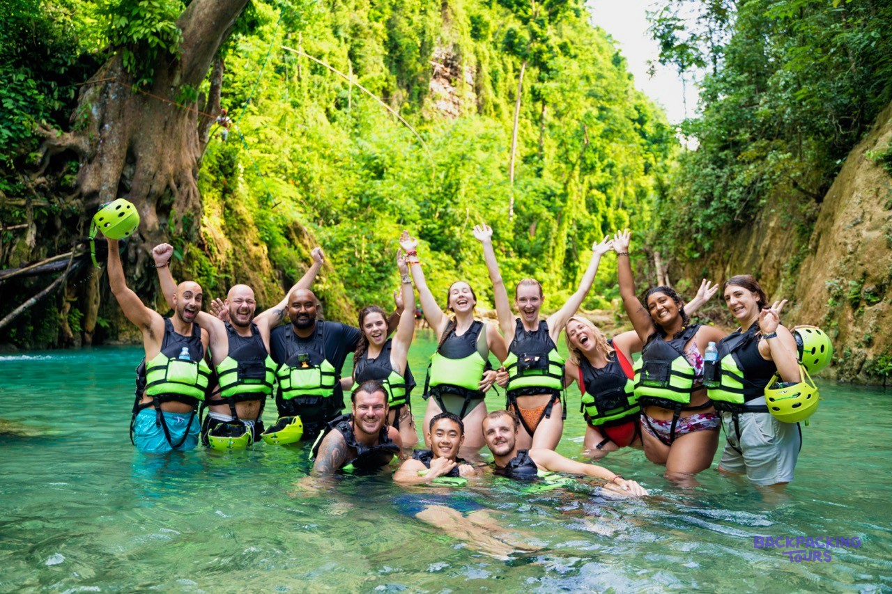 A group of travellers in helmets and life jackets canyoneering at Kawasan Falls.