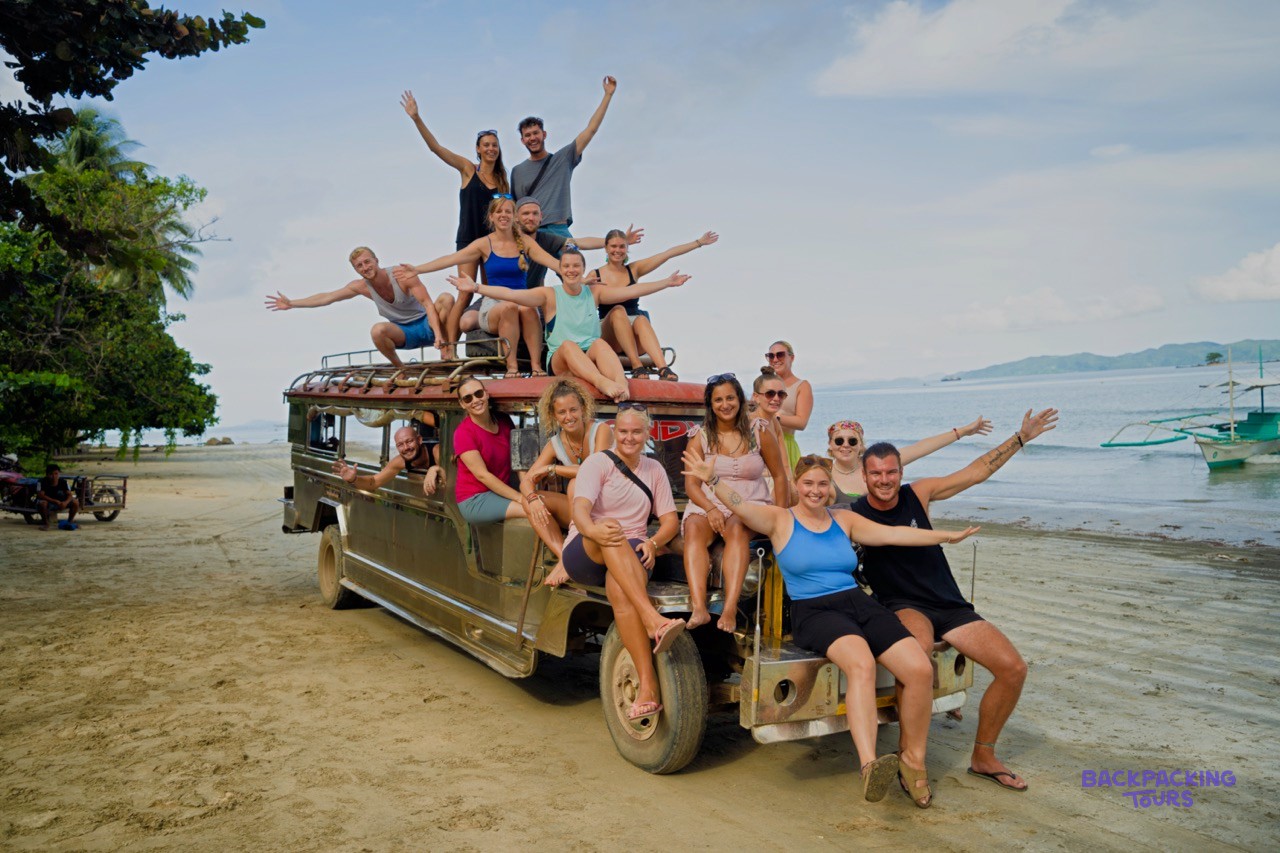 A group of backpackers riding through Palawan in a colourful local jeepney.
