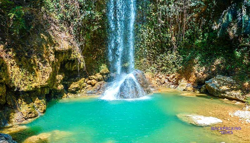 A traveller cooling off under a turquoise waterfall on the island of Cebu.
