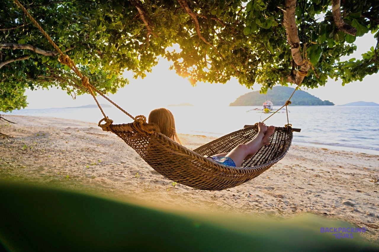 A traveller relaxing in a hammock at a beach camp on a remote Palawan island.