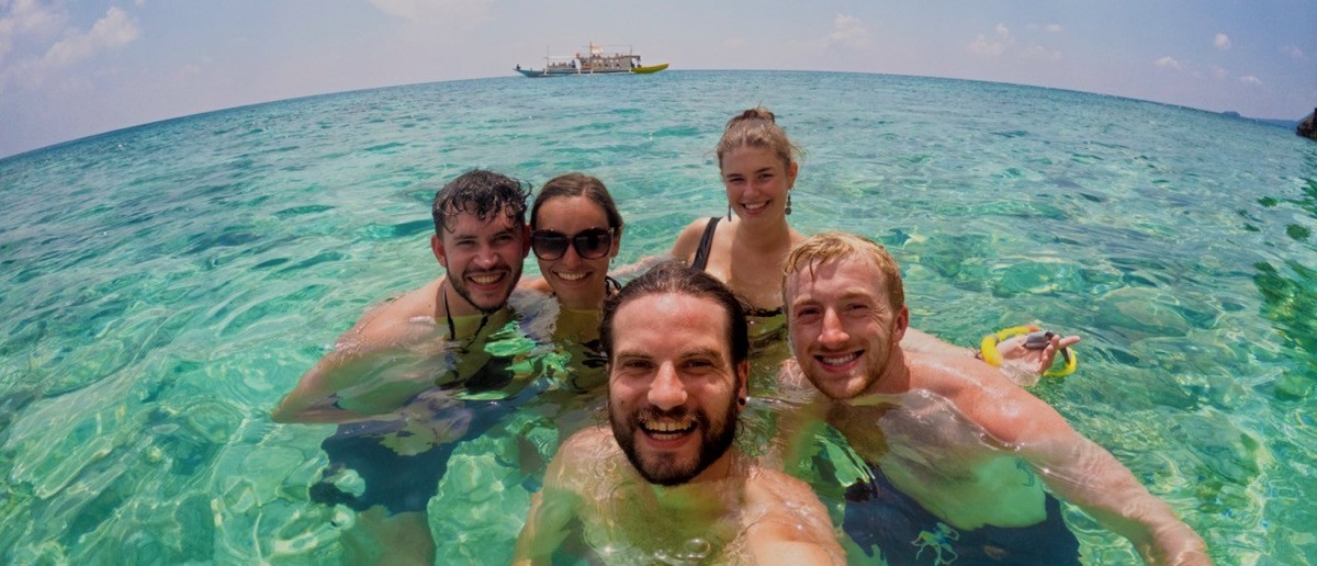 Friends taking a selfie on a deserted beach during the Palawan boat expedition.