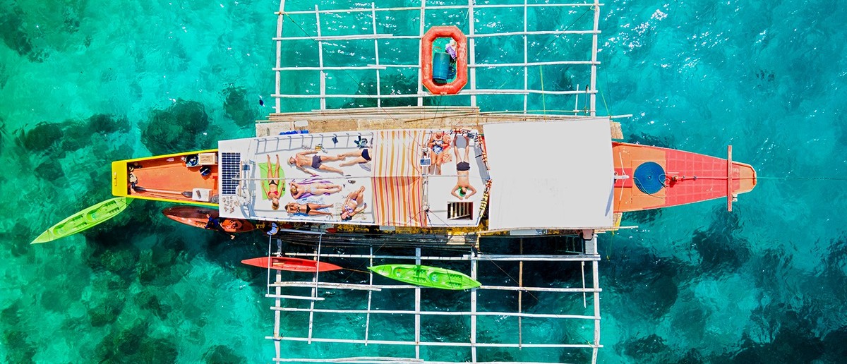 Travellers relaxing on the roof of a traditional Banca boat in Palawan.