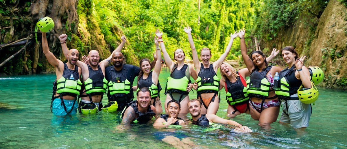 A group of travellers in helmets and life jackets canyoneering at Kawasan Falls.