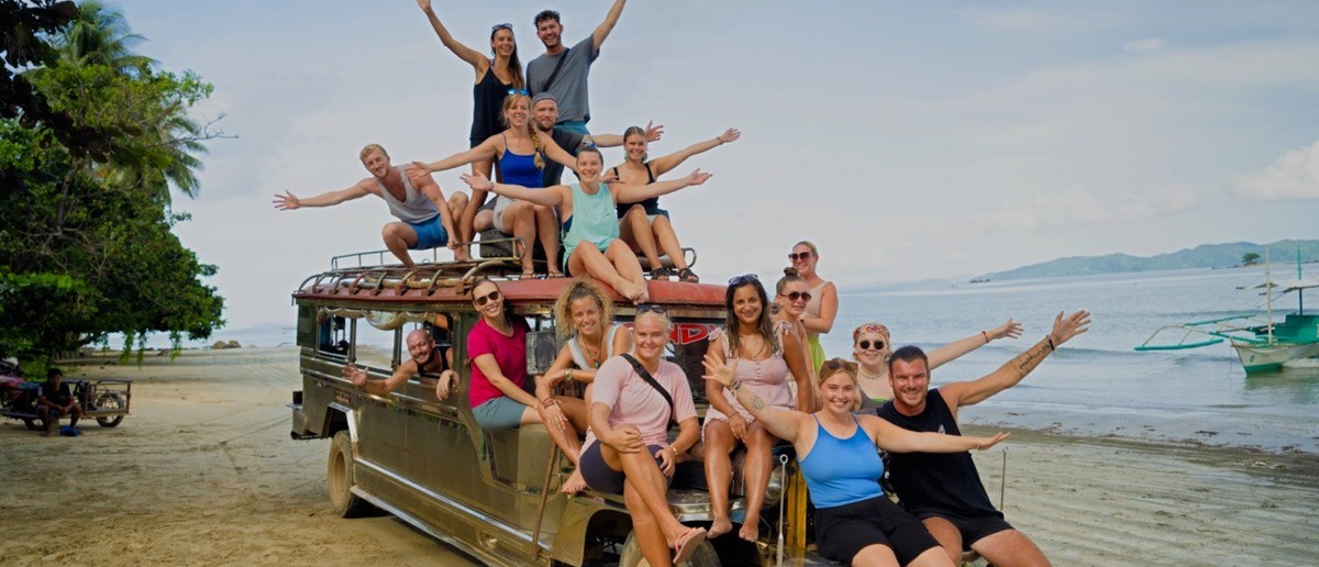 A group of backpackers riding through Palawan in a colourful local jeepney.