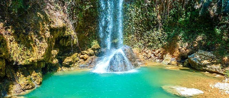 A traveller cooling off under a turquoise waterfall on the island of Cebu.