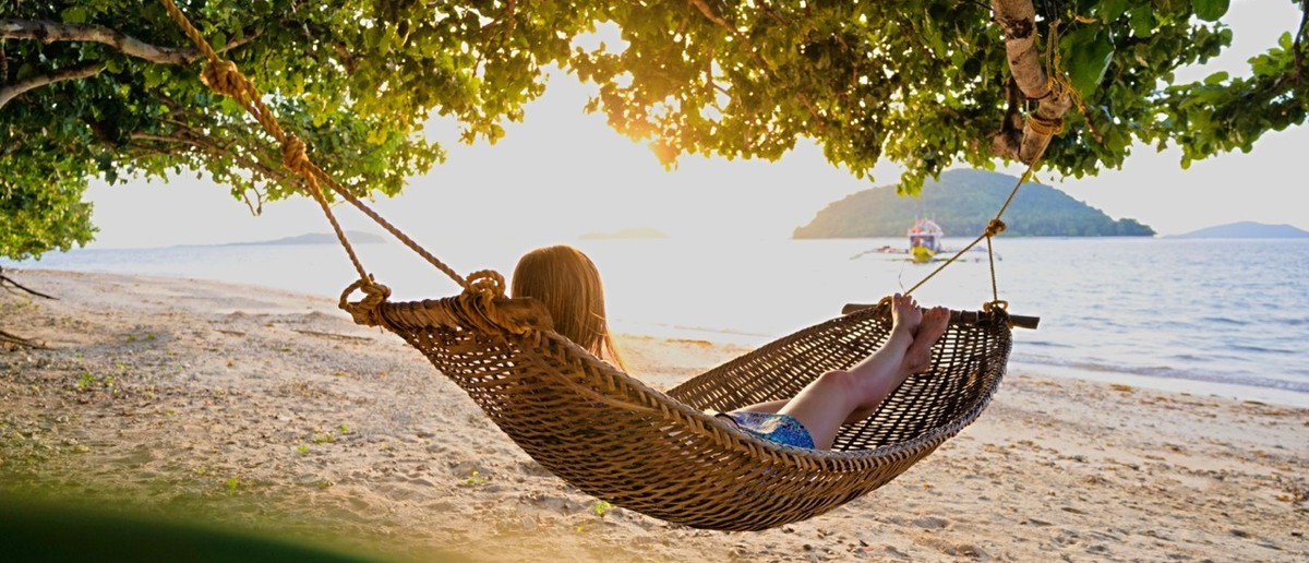 A traveller relaxing in a hammock at a beach camp on a remote Palawan island.
