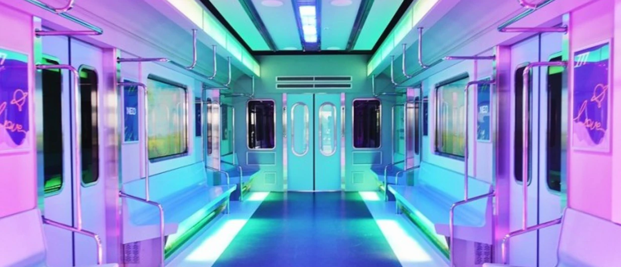 An empty, futuristic Seoul subway car interior glowing with vibrant neon pink, blue, and green lights.