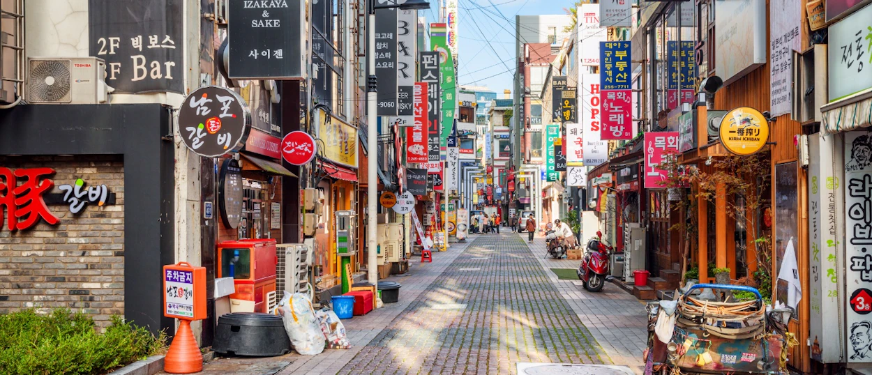 A lively street in Seoul, South Korea, with numerous shops and colorful Korean signs.
