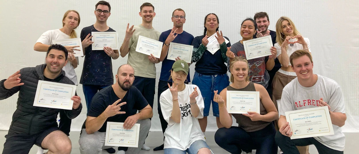 A diverse group of happy travelers posing with K-pop dance class certificates in Seoul.