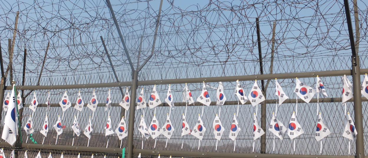 Small South Korean flags adorn a barbed wire fence at the Demilitarized Zone.