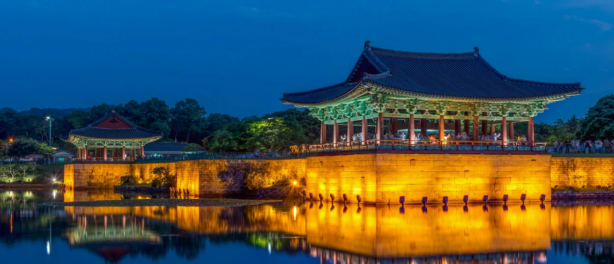 Illuminated traditional Korean pavilions reflect in Anapji Pond at night, creating a serene scene in Gyeongju.