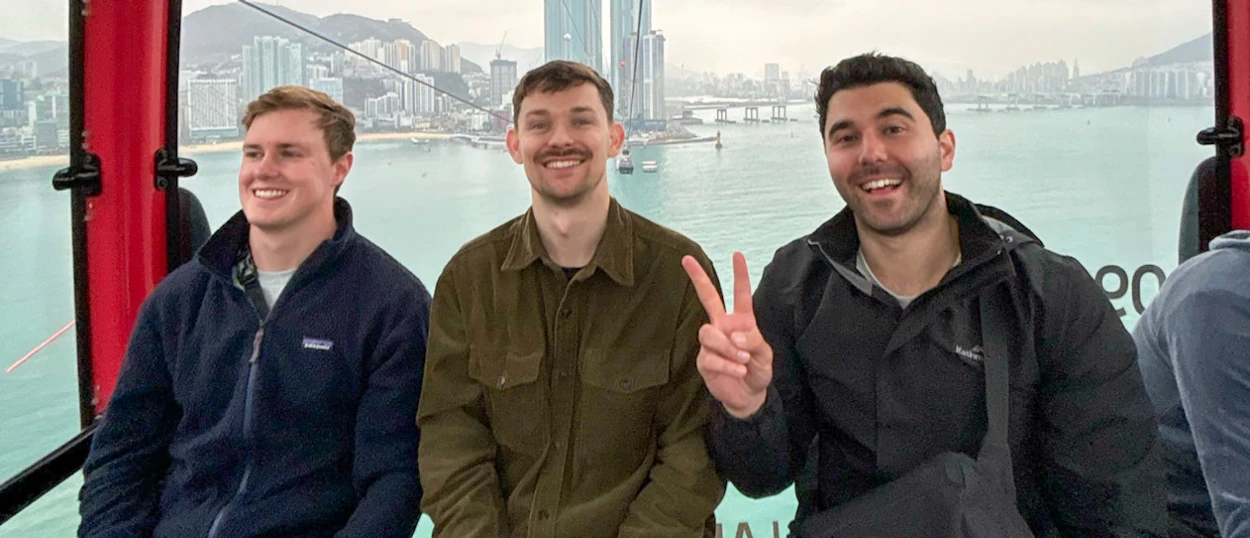Three happy men ride the Songdo cable car, enjoying panoramic city and ocean views in Busan.