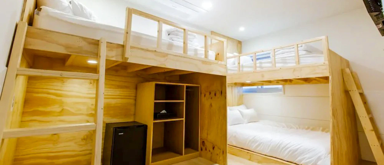 A cozy hostel room in Seoul with light wood bunk beds, a single bed, and storage.