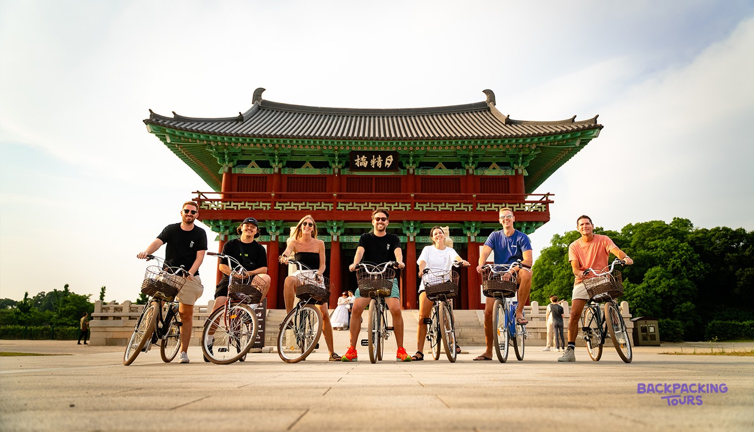 A group of cyclists lined up with their bikes in front of a traditional gate in Gyeongju.