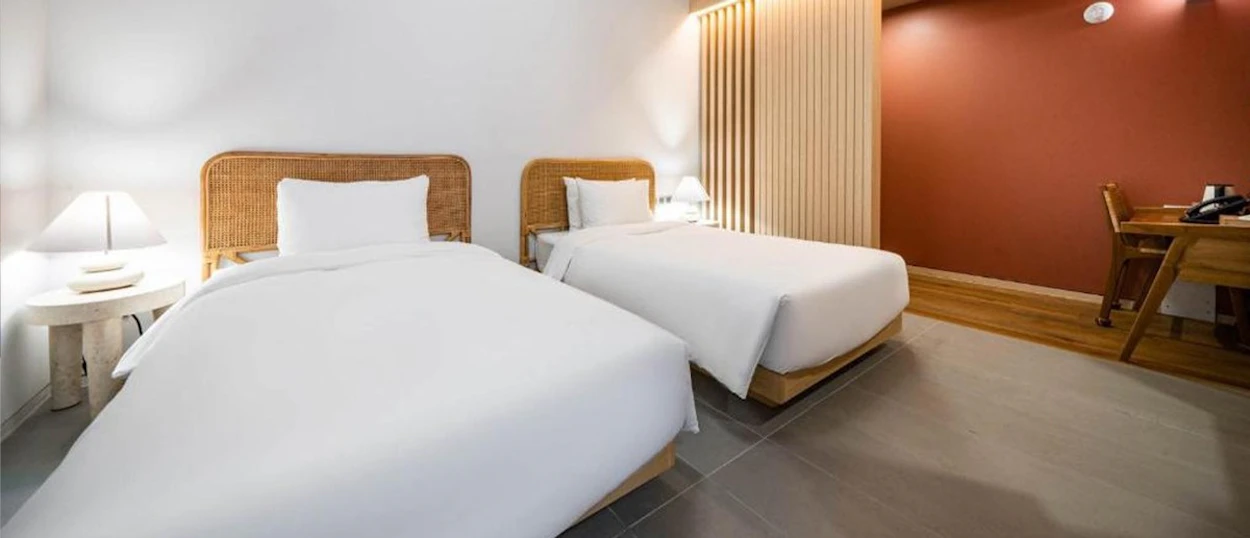 A twin room at the Hound Hotel Haeundae in Busan with woven headboards and white linen.