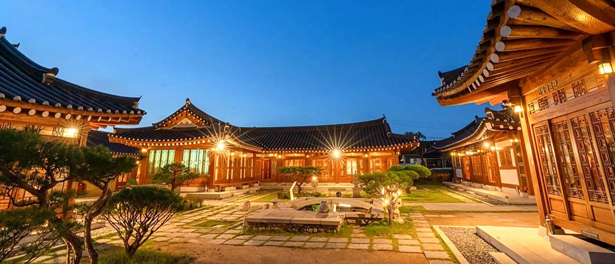 The courtyard of a traditional hanok village in Gyeongju lit up at dusk.