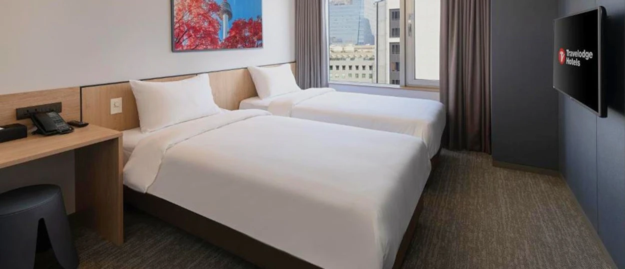 A twin hotel room at the Travelodge Myeongdong Namsan in Seoul with two neatly made beds.