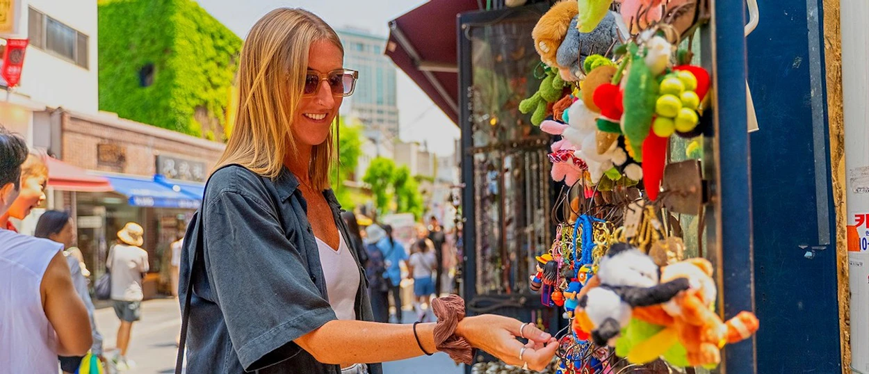 A traveller browsing colourful souvenir stalls on a busy Seoul street.
