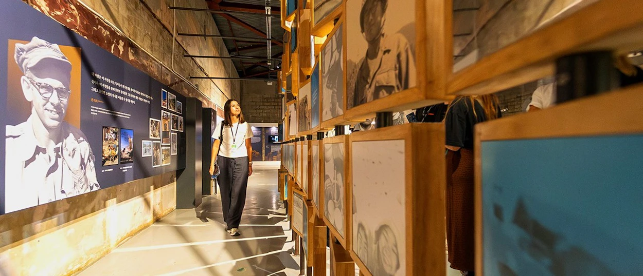 A visitor walking through the DMZ exhibition hall past displays on the Korean War.