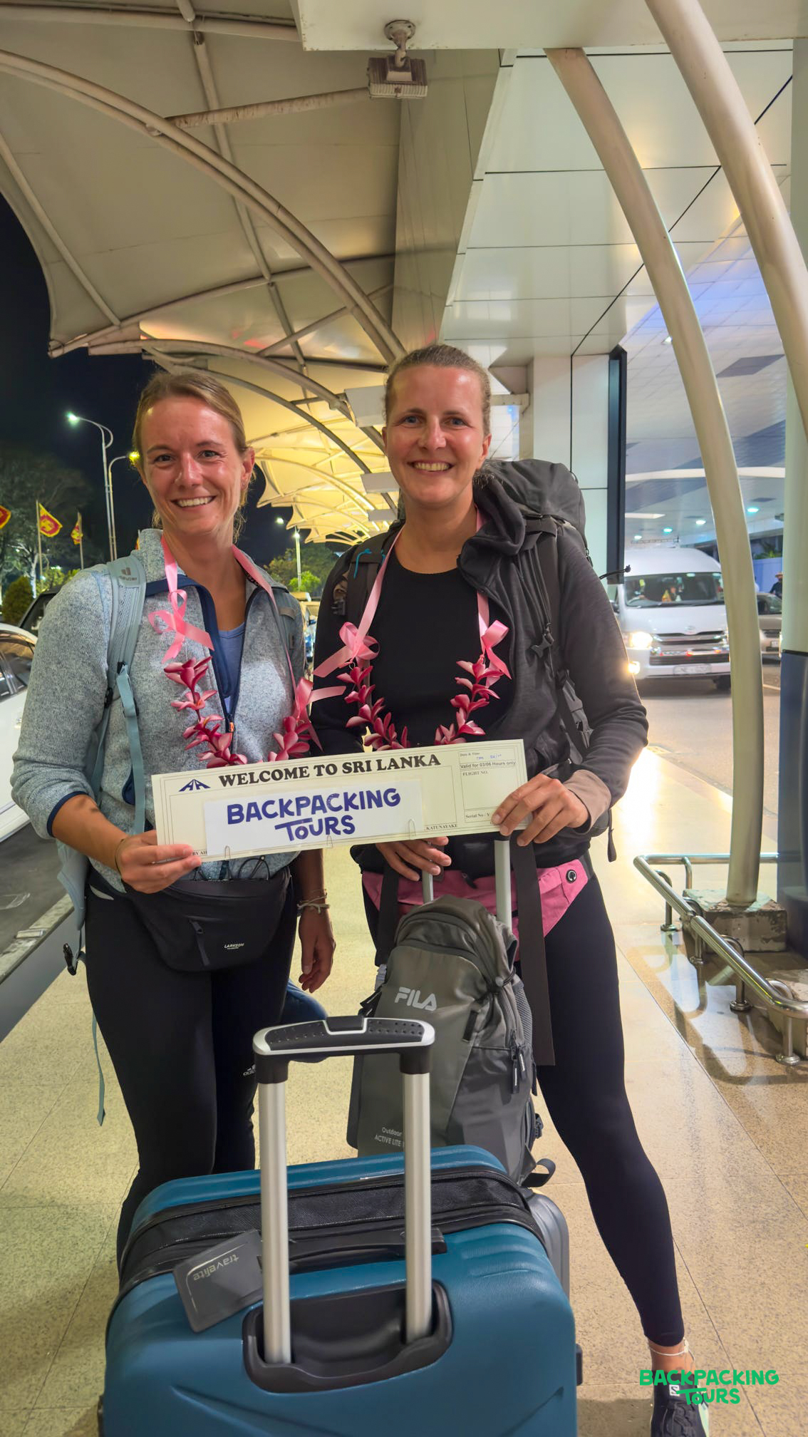 Smiling women with leis and a welcome sign arrive in Colombo for their Sri Lanka tour.